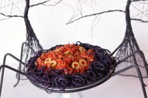 A spider plate filled with black spaghetti, meat sauce and topped with green olives. .