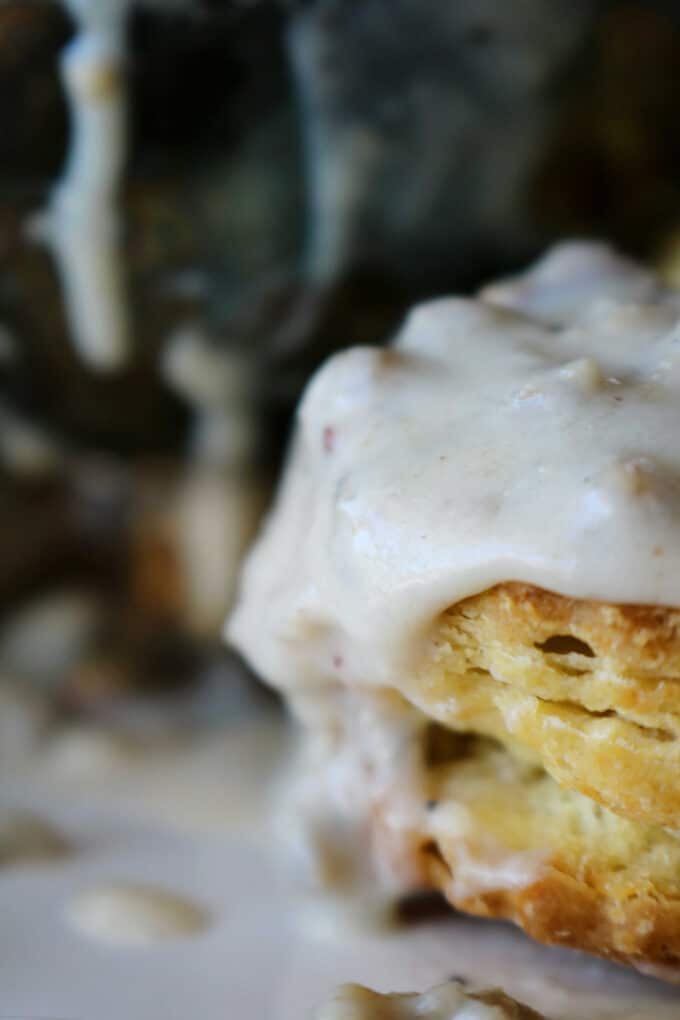 One homemade biscuit that has gravy dripping on down the side of it. 