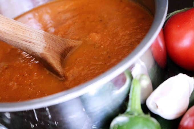 Ranchero Sauce pureed in a saucepan with a wooden spoon resting on the side.