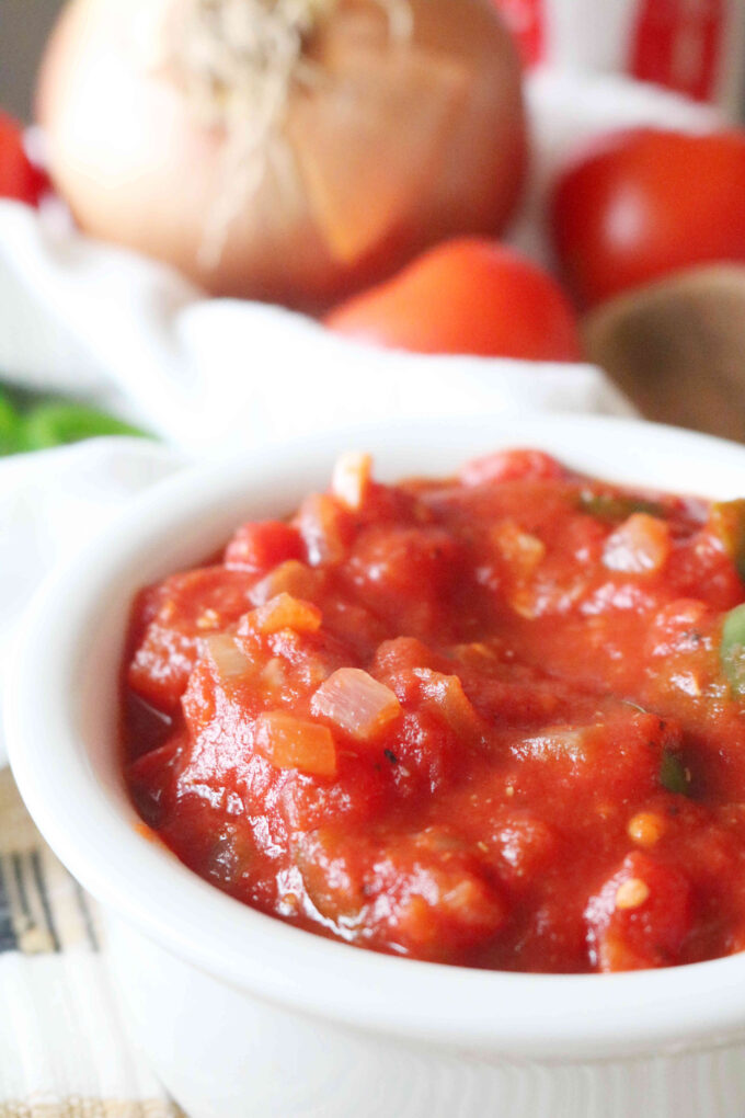 A close up shot of Easy Ranchero Sauce in a bowl with fresh produce in the background.