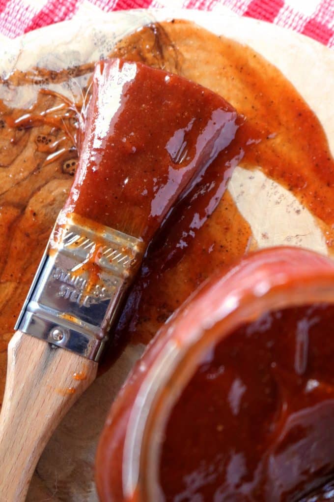 A close up overhead shot of a basting brush covered in barbecue sauce. 