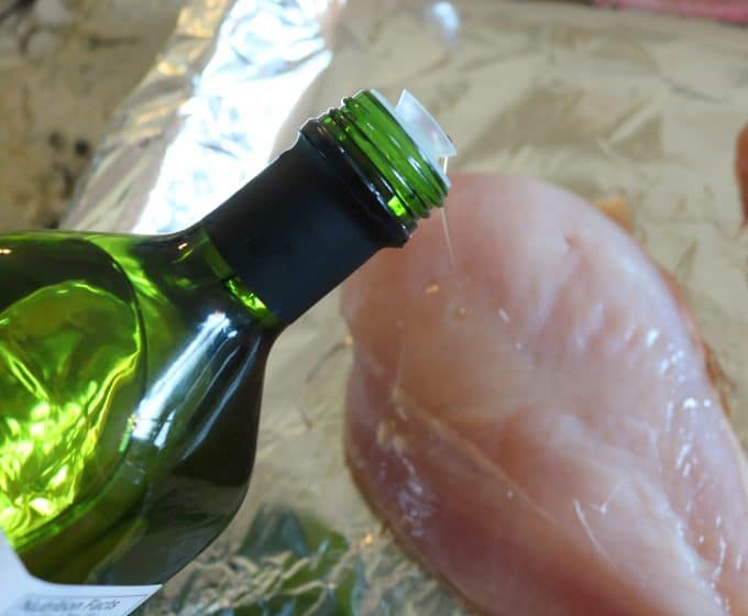 Drizzling chicken breasts with oil.