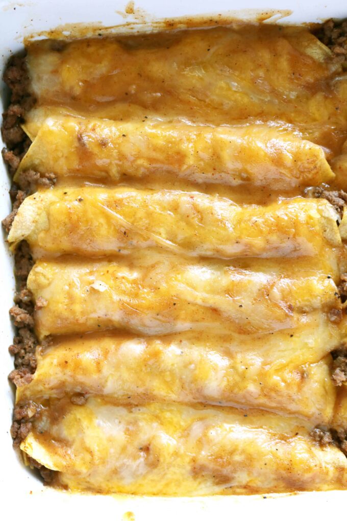 A close up shot of Tex Mex Beef Enchiladas in a rectangle white baking dish. 