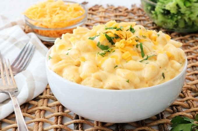 Shells and Cheese served in a white bowl topped with fresh parsley and freshly grated cheese. 