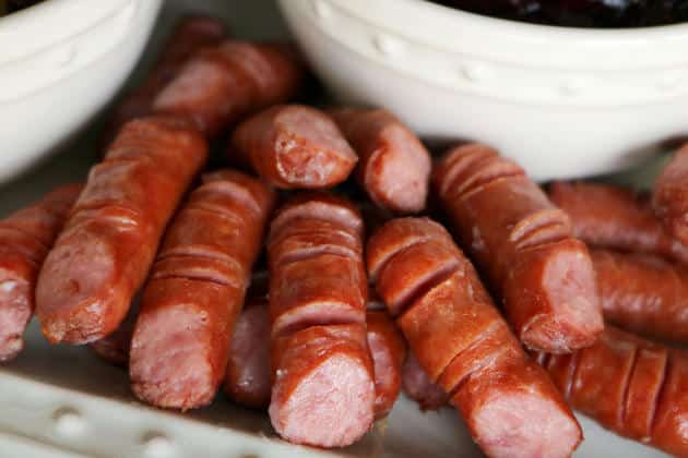 A Halloween appetizer featuring lil' smokies cut to look like fingers that are placed on a white serving dish. 