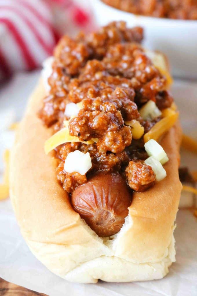 A close up shot of a hot dog in a bun topped with coney sauce. 