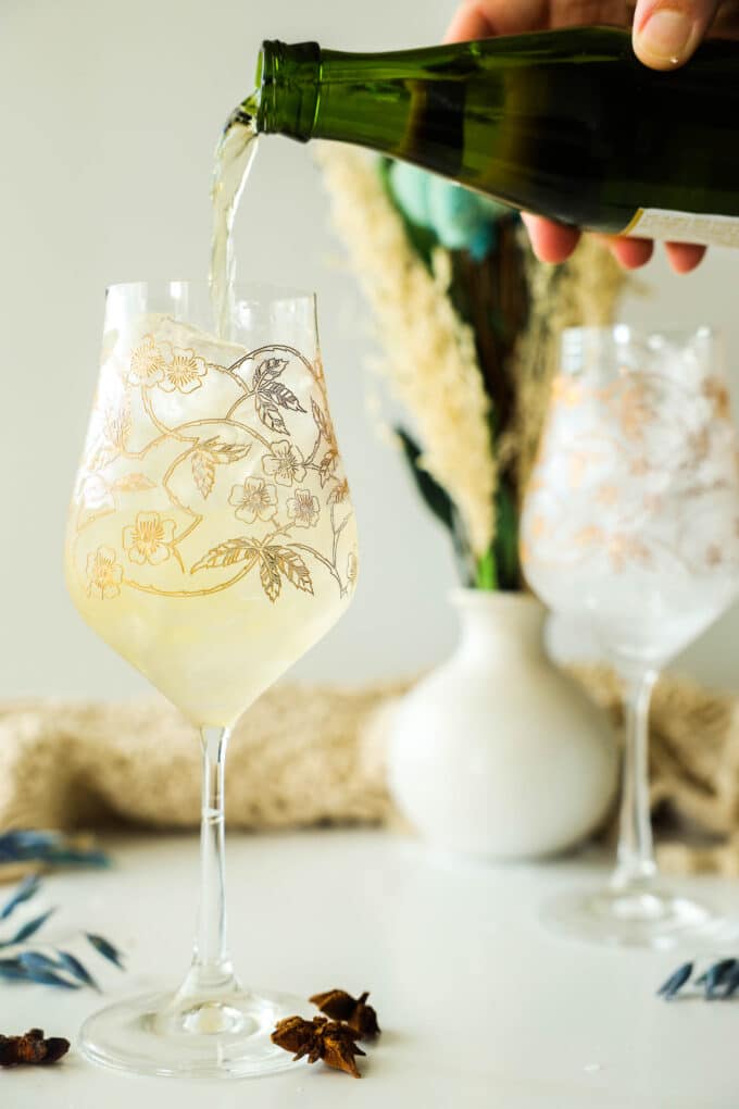 a hand pouring sparkling cider into a wine glass.