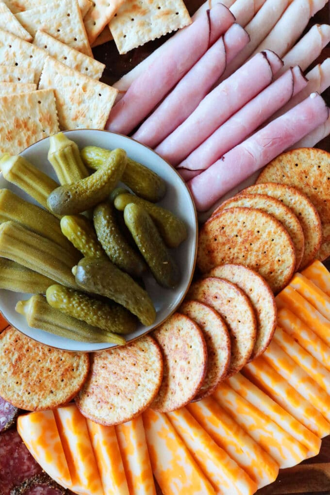 An overhead shot of a Meat and Cheese Tray with rolled deli meats, crackers and sliced cheeses.
