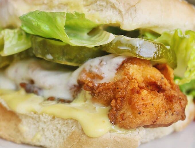 A close up shot of a crispy chicken sandwich that is oozing with honey mustard.