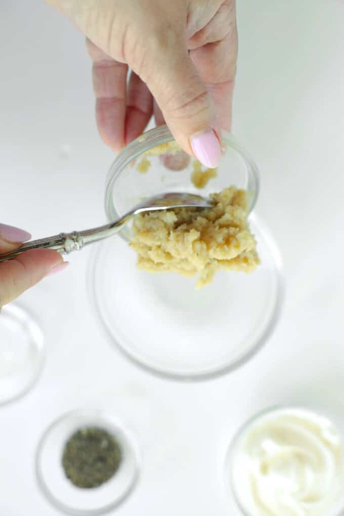 Spoonful of prepared horseradish being added to a mixing bowl