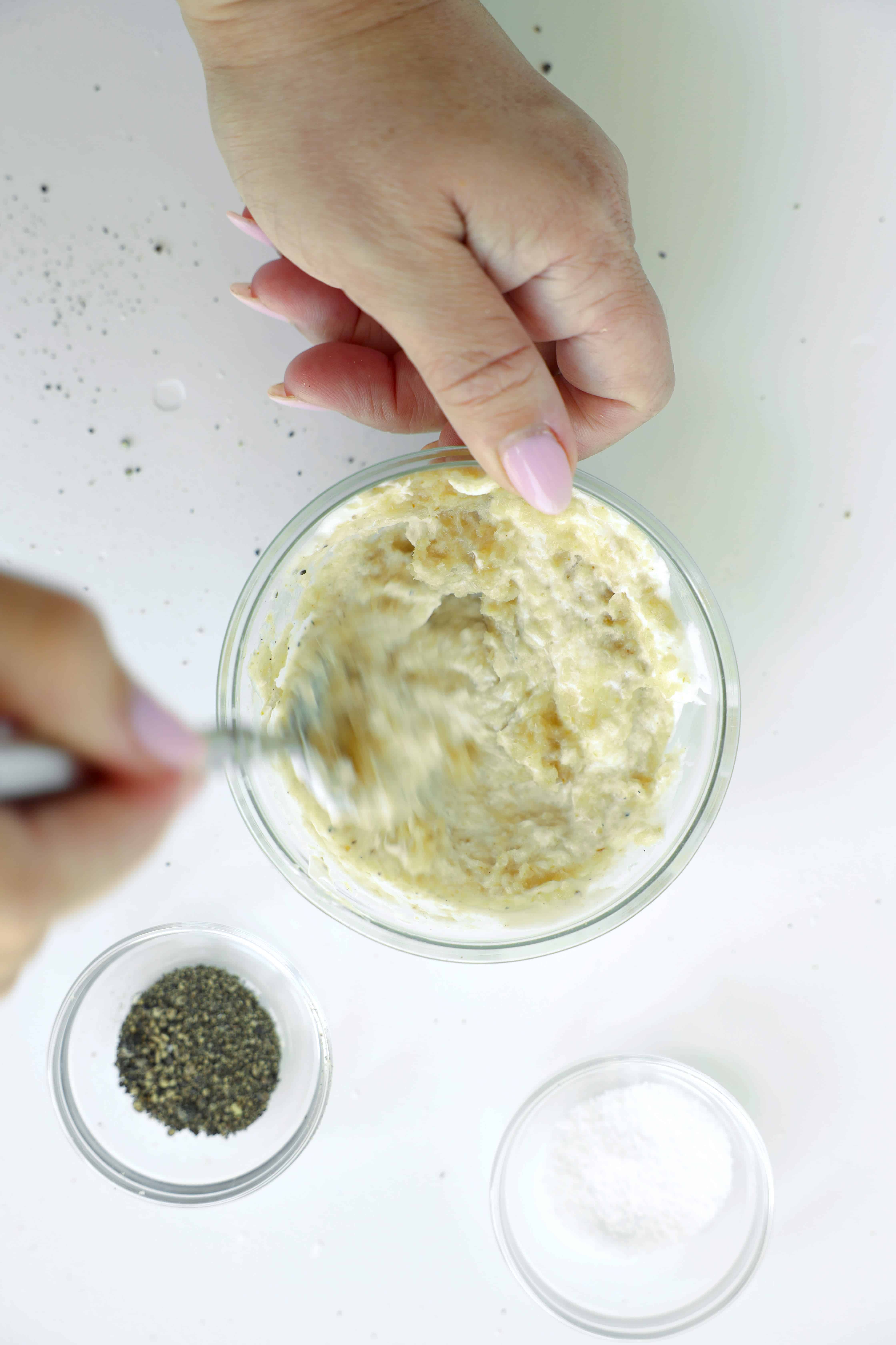 Mixing prepared horseradish and sour cream in a glass bowl