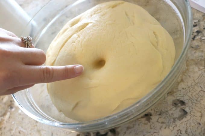 A hand poking a hole in the dough for the first rise poke test.
