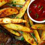 Crispy oven-baked steak fries served with ketchup and steak, garnished with fresh parsley.