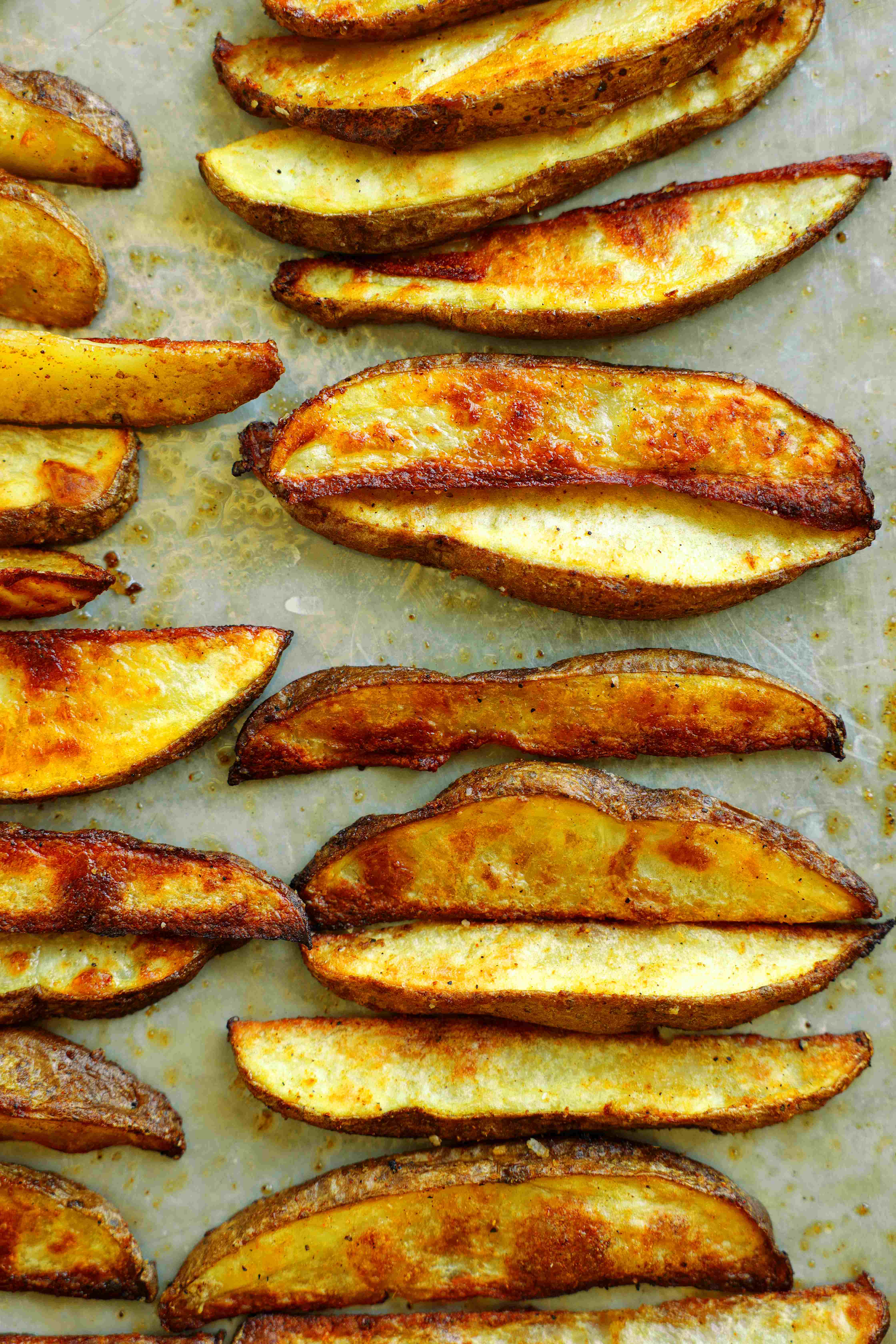Close-up of crispy homemade oven-baked steak fries with golden brown edges on a sheet pan.