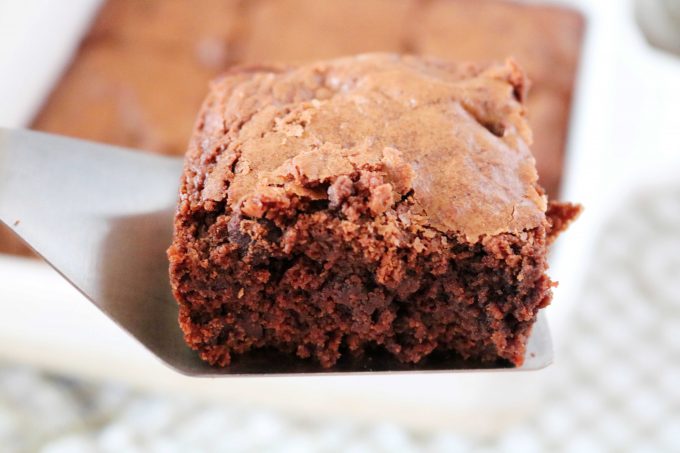 A square slice of Chocolate Brownies being held on a spatula over the baking dish. 