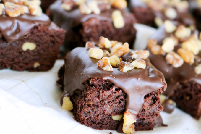 Fudgy Brownies with Walnuts cut into squares spaced out on a white napkin. 