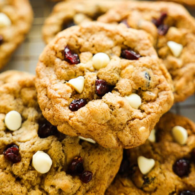 A close up of a little pile of Oatmeal Cranberry Cookies. They are golden brown and there are dried cranberries and white chocolate chips visible.