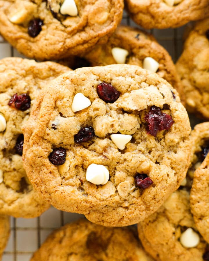 Golden brown Oatmeal Cranberry Cookies sit piled up on a wire rack.