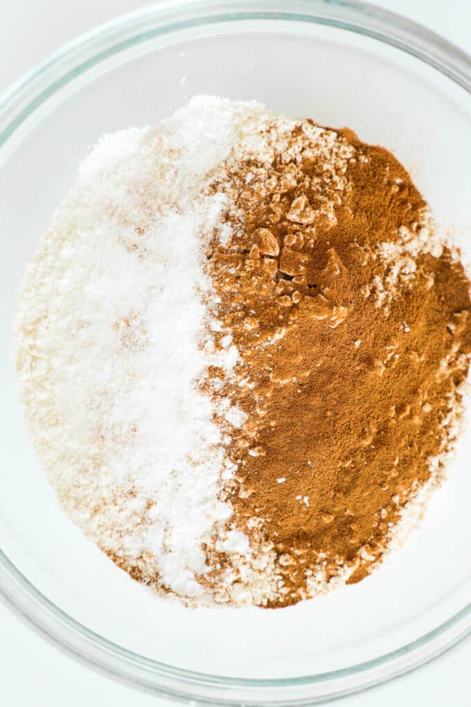Flour, baking soda, baking powder, and cinnamon in a bowl, before being mixed. 