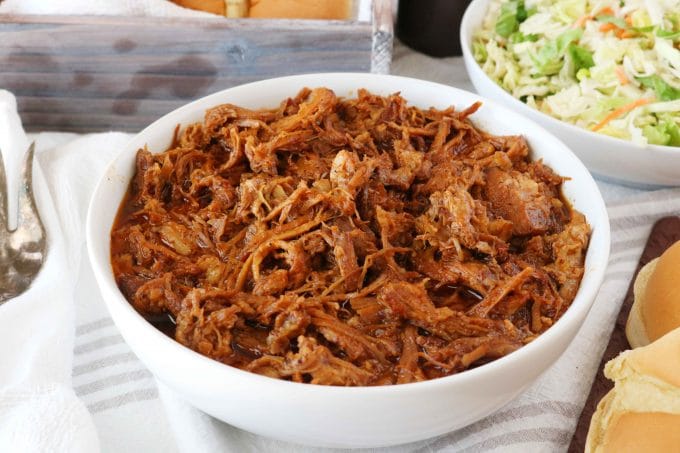 A bowl of BBQ Pulled Pork with another bowl of shredded cabbage in the background. 