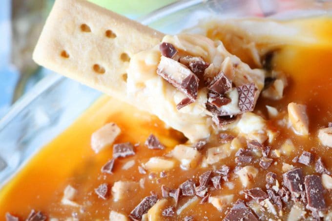 A close up shot of Caramel Apple Dip with Cream Cheese and Toffee with a rectangular cookie sitting in the dip. 