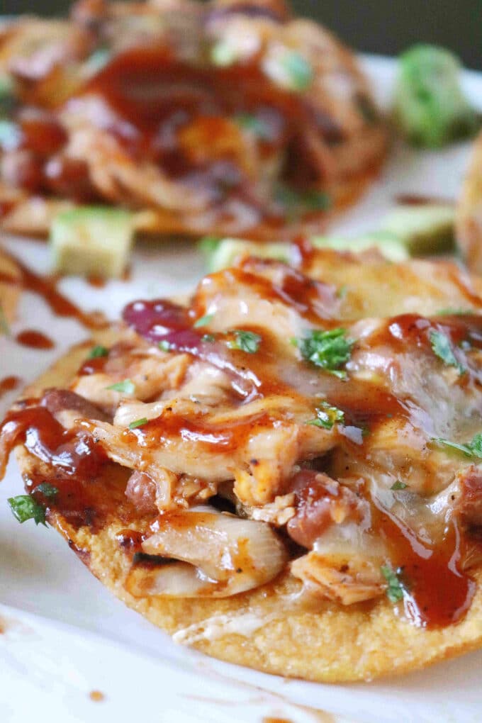 A close up shot of BBQ chicken tostada. In the background are more tostadas. 