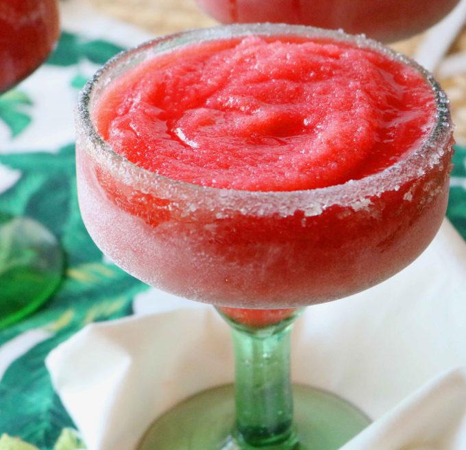 A close up shot of frozen strawberry margaritas served in a margarita glass. 