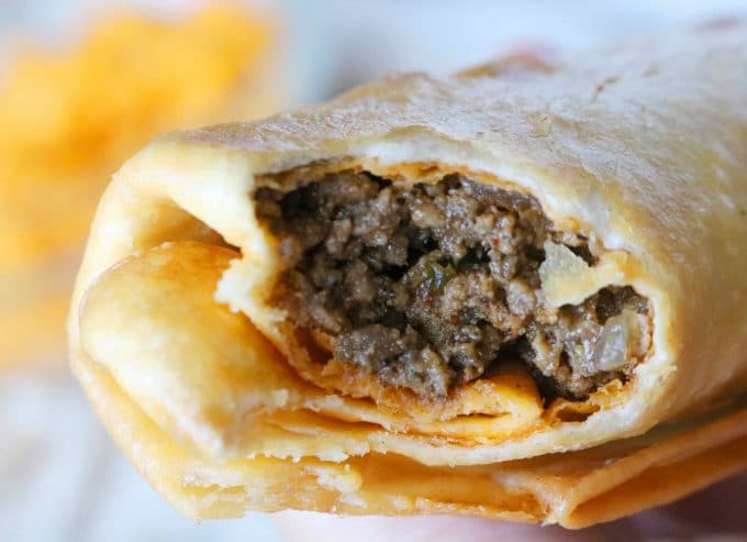 A close up shot of a bite missing from a beef chimichanga. 