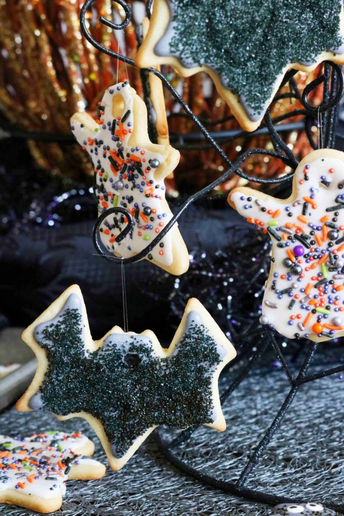 Hanging black bat cookies and white ghost cookies from a black metal stand. 