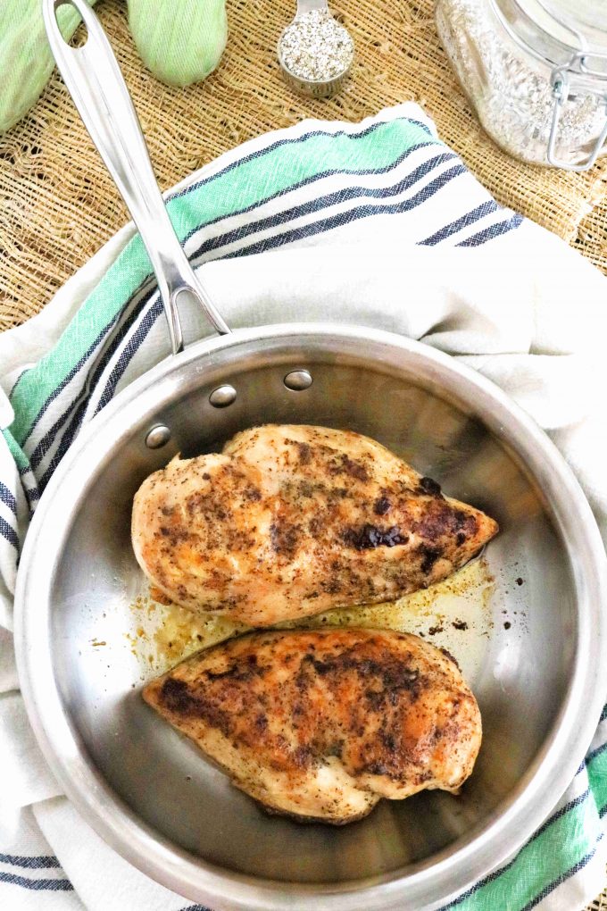Pan-Seared Chicken in a pan with seasoning off to the side.