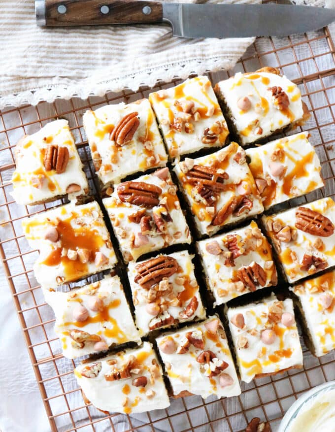 An overhead shot of butter pecan blondies cut into squares that are sitting on top of a wire cooling rack. At the top of the image is a wood handle knife. 