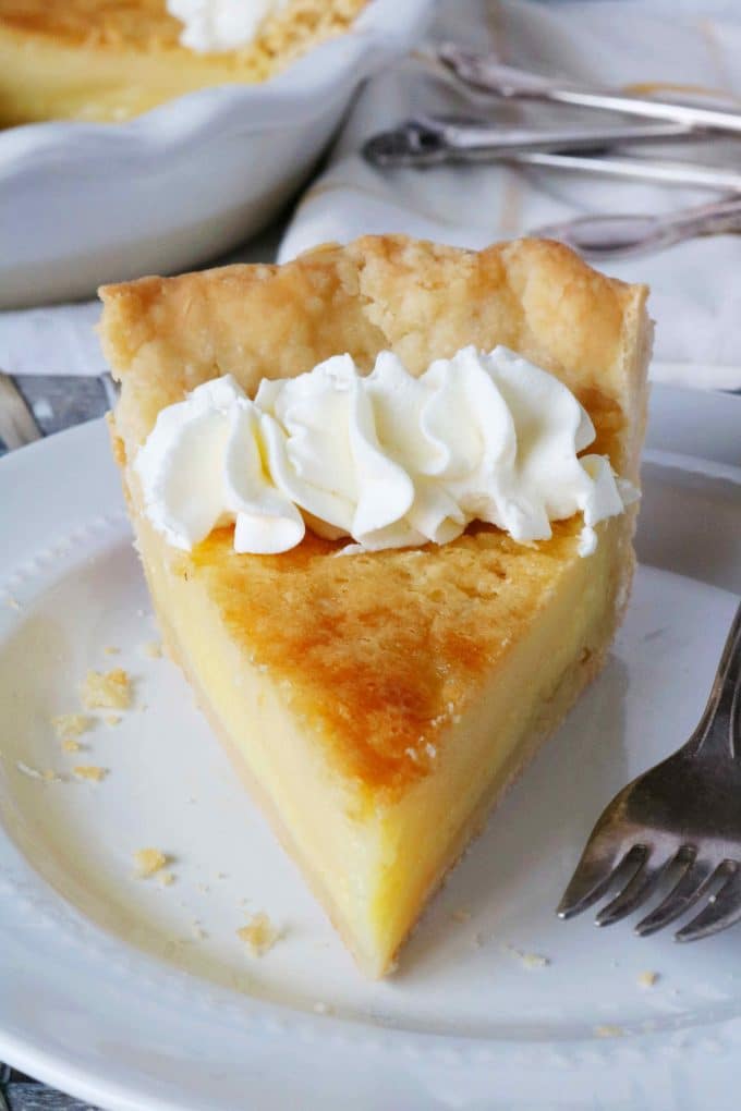 A close up shot of a slice of buttermilk pie served on a white plate. 