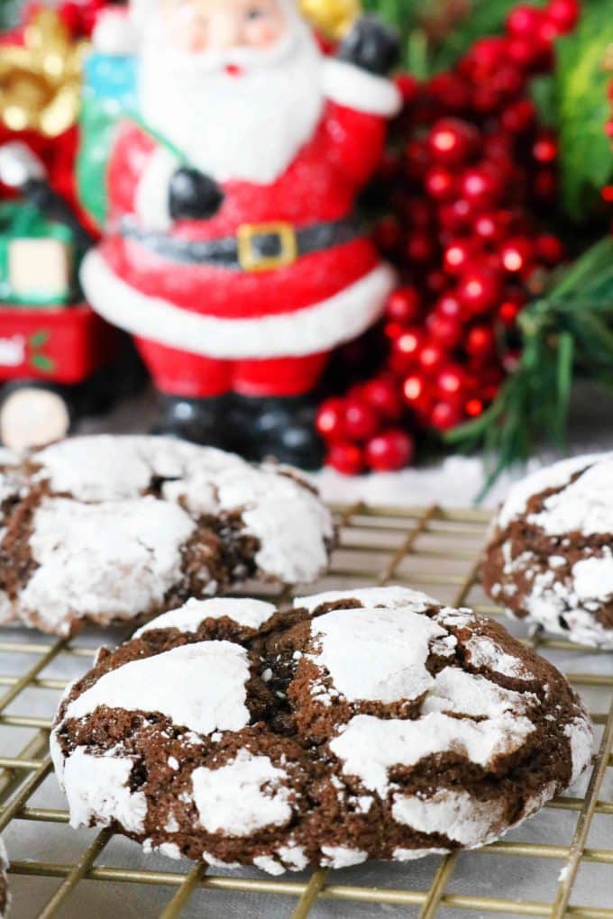 Chocolate crackles cookies on a wire cooling rack with a ceramic Santa standing in the background. 