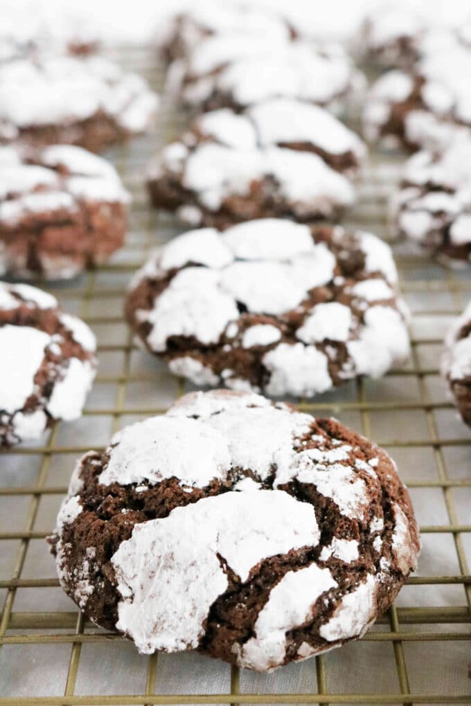 A line of chocolate crackle cookies sitting on a wire cooling rack. 