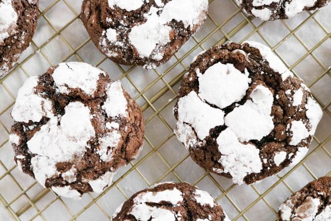 An overhead shot of chocolate crackle cookies sitting on top of a wire cooling rack.