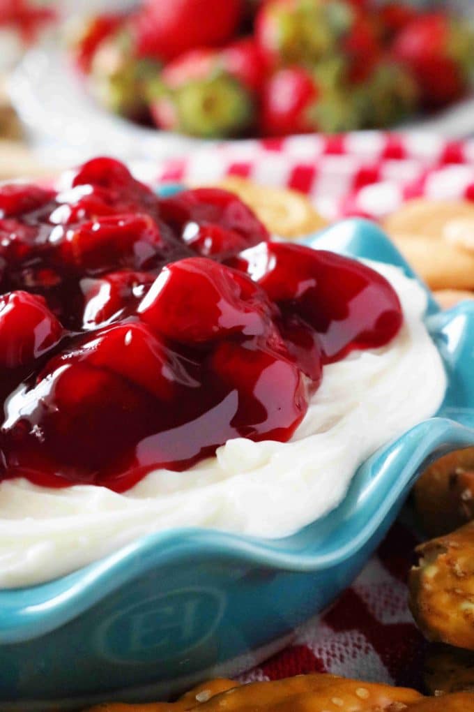 A close up shot of cherry cheesecake dip served in a teal scalloped bowl. 