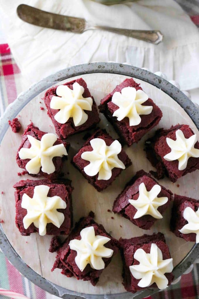 An overhead shot of red velvet brownies topped with cream cheese frosting shaped like flowers. 