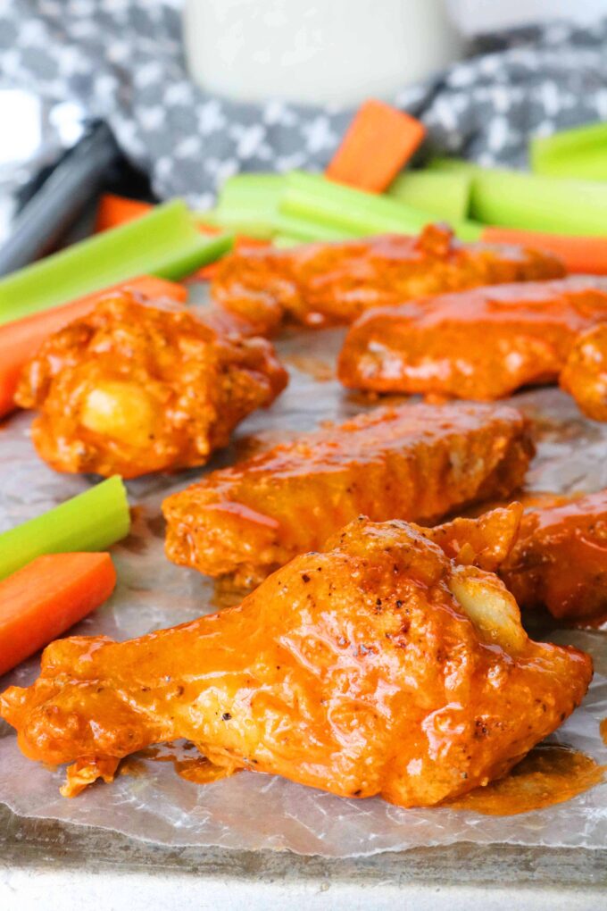 A close up shot of a wing drumette coated in buffalo sauce.