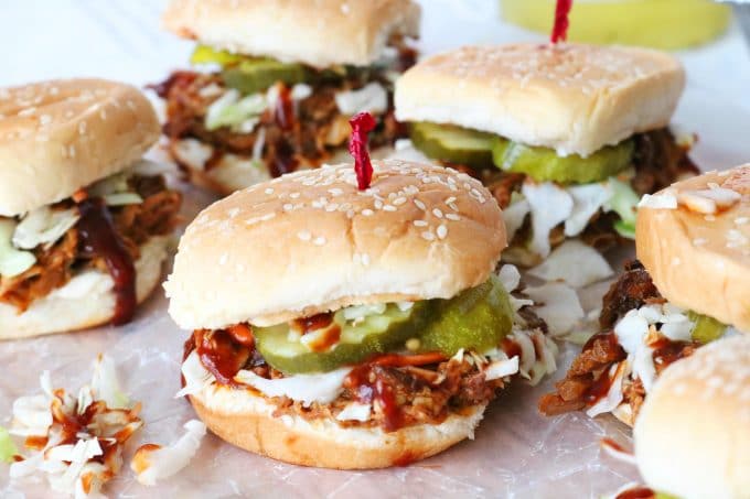 A group of Pulled Pork Sliders placed on parchment paper. 