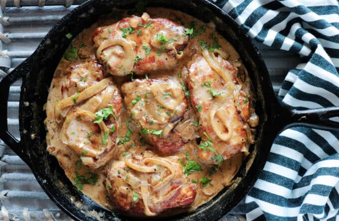 An overhead shot of Smothered Pork Chops cooked in a cast iron skillet. 