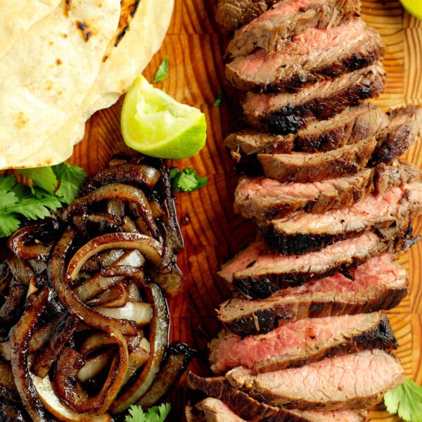 Sliced al Carbon Tacos with sides of grilled onions and lime