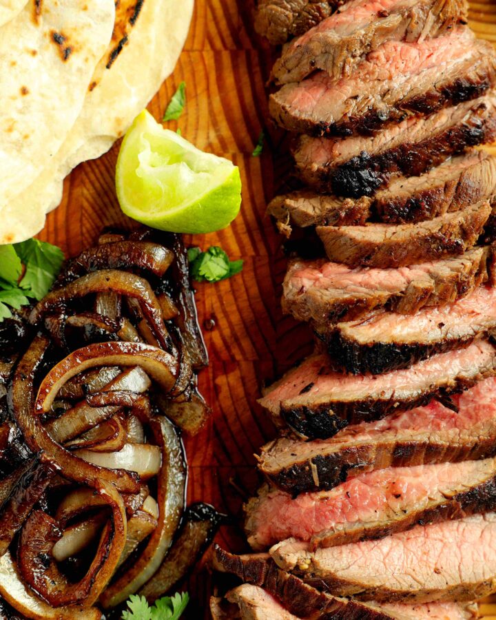 Sliced al Carbon Tacos with sides of grilled onions and lime