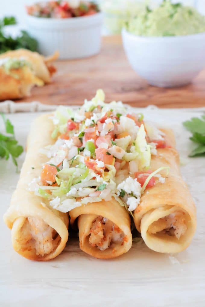 Three Chicken Flautas topped with pico de gallo and lettuce. 
