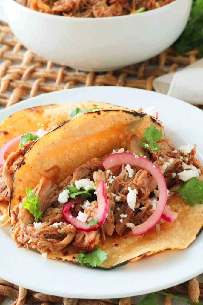 Pulled pork tacos served on a white plate. 