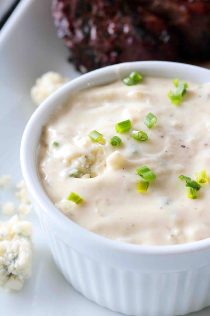 A small ramekin of Gorgonzola Sauce with green onions sprinkled on top. 