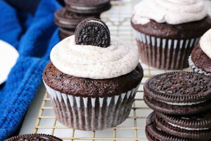 Oreo Cupcakes on a cooling rack with a stack of oreos sitting next to the cupcake. 