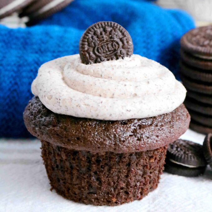 A close up of one Oreo Cupcake with a mini oreo sitting on top of the cupcake.
