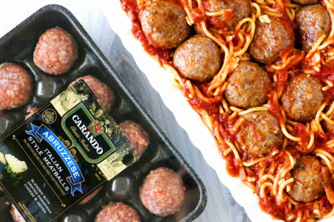 An overhead shot of meatball casserole with a package of uncooked meatballs sitting next to the dish. 