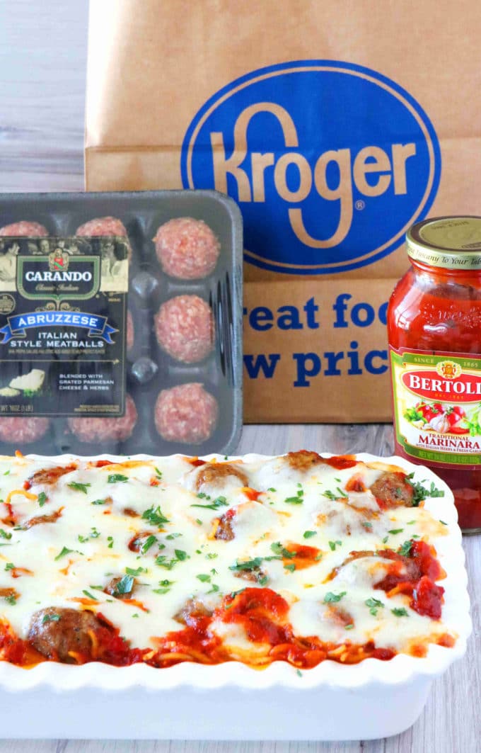 A shot of cooked meatball casserole, a package of uncooked meatballs, a jar of marinara and a brown Kroger bag. 