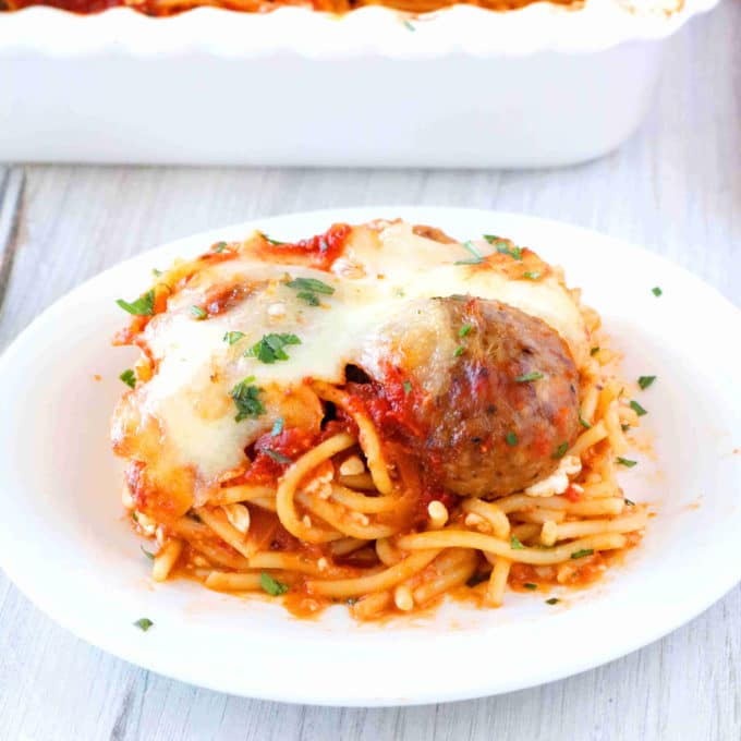  A side view of a slice of Meatball Casserole served on a white plate. 